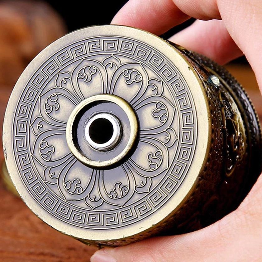 Bottom view of Buddhist prayer wheel car ornament showing lotus flower engraving and mounting hole held in hand
