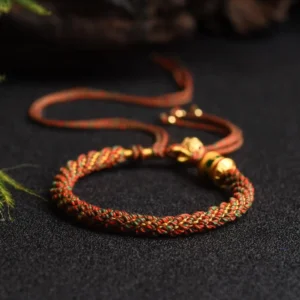 Red and green Buddhist prayer wheel braided string bracelet with gold metal charms and beaded tassel, handwoven with adjustable fit