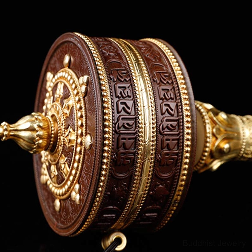 Front-facing Buddhist prayer wheel with gilded Dharma wheel motif and intricately engraved border trim detail