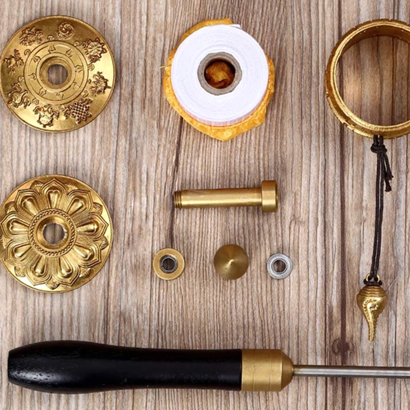 Buddhist prayer wheel DIY assembly kit components: metal parts, wooden handle, mantra discs, and Sanskrit prayer paper roll