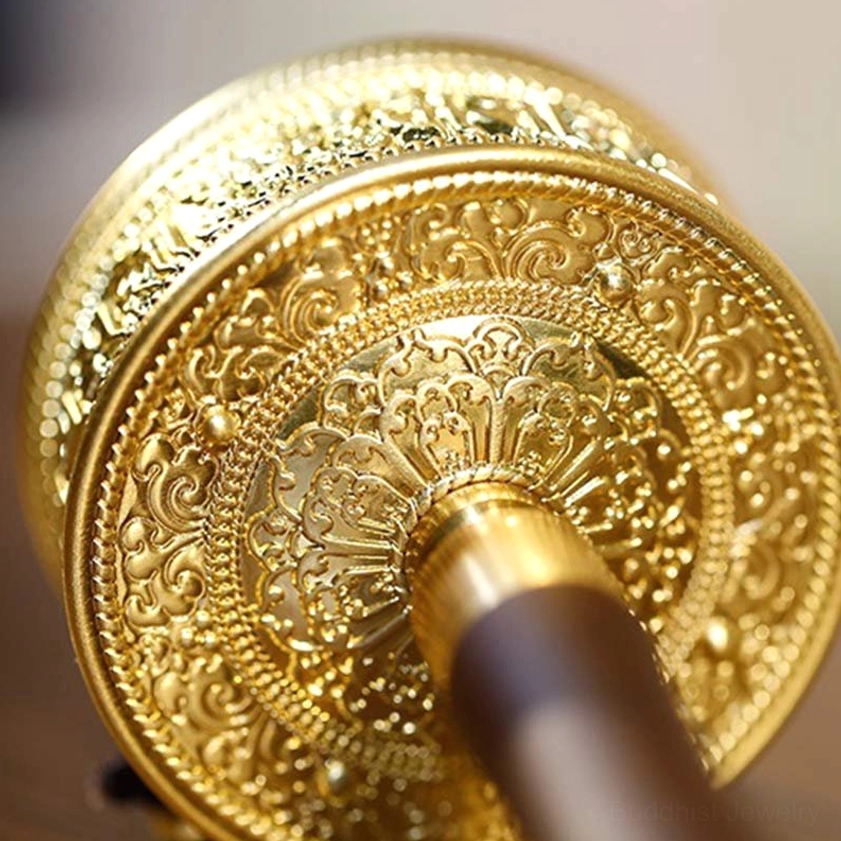 Buddhist prayer wheel barrel detail, close-up of embossed Buddhist floral patterns and metal handle joint, showing rich artistic hand-engraving