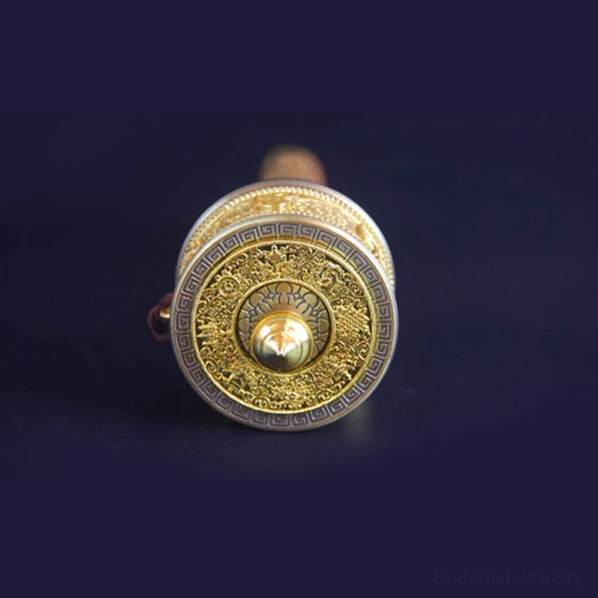 Prayer wheel main body top view featuring pointed brass cap and floral embossed mantra design