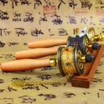 Multiple handcrafted Buddhist prayer wheels with wooden handles displayed from overhead angle, showing intricate metal work and gemstone inlays