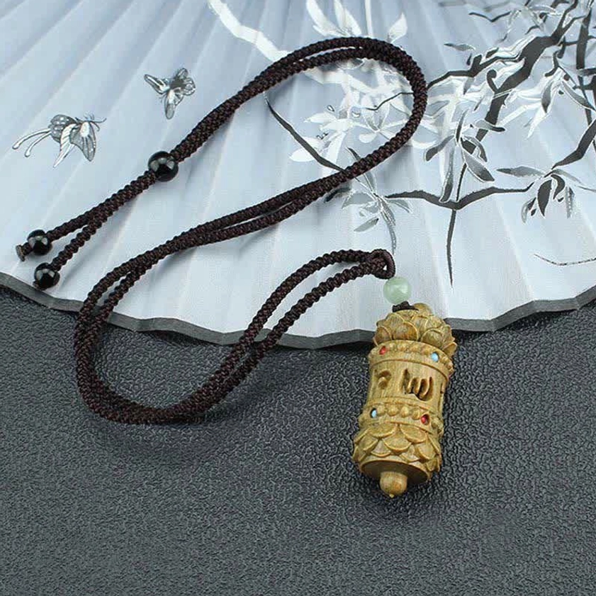 Braided rope Buddhist pendant necklace in dark brown with light green aventurine spacer bead displayed flat on textured surface