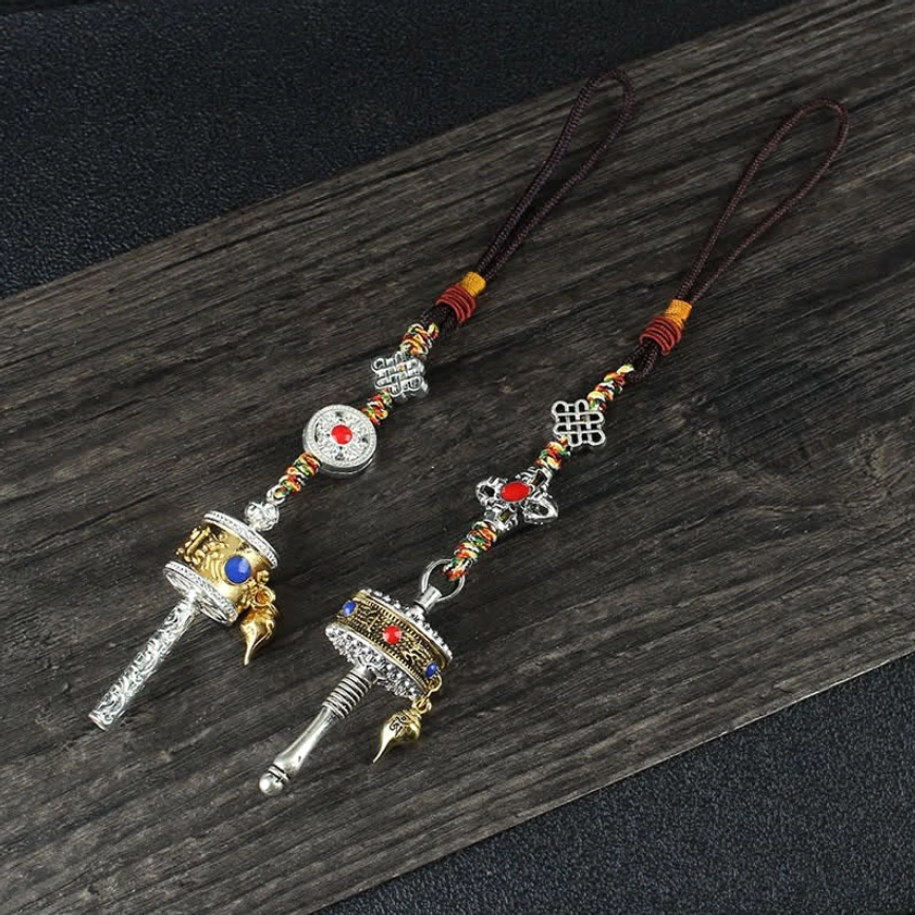 Pair of Buddhist prayer wheel pendants with two-tone metal, colorful braided ropes, and decorative round plates