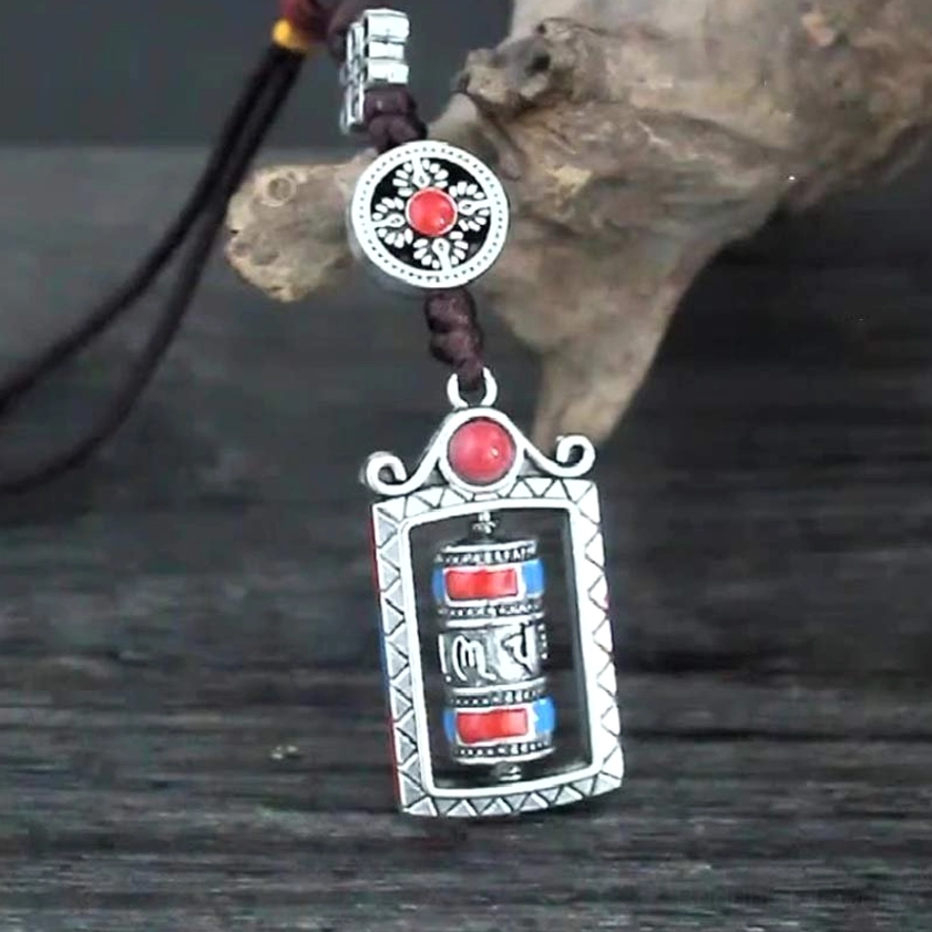Buddhist prayer wheel pendant with red-centered round charm and closed metal frame design