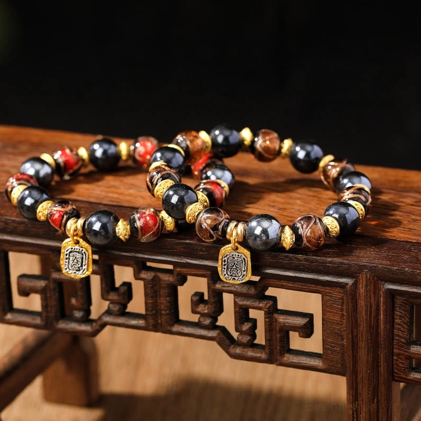 Two Buddhist wealth goddess bracelets displayed together on traditional wooden stand showing mixed earth-tone and blue bead varieties