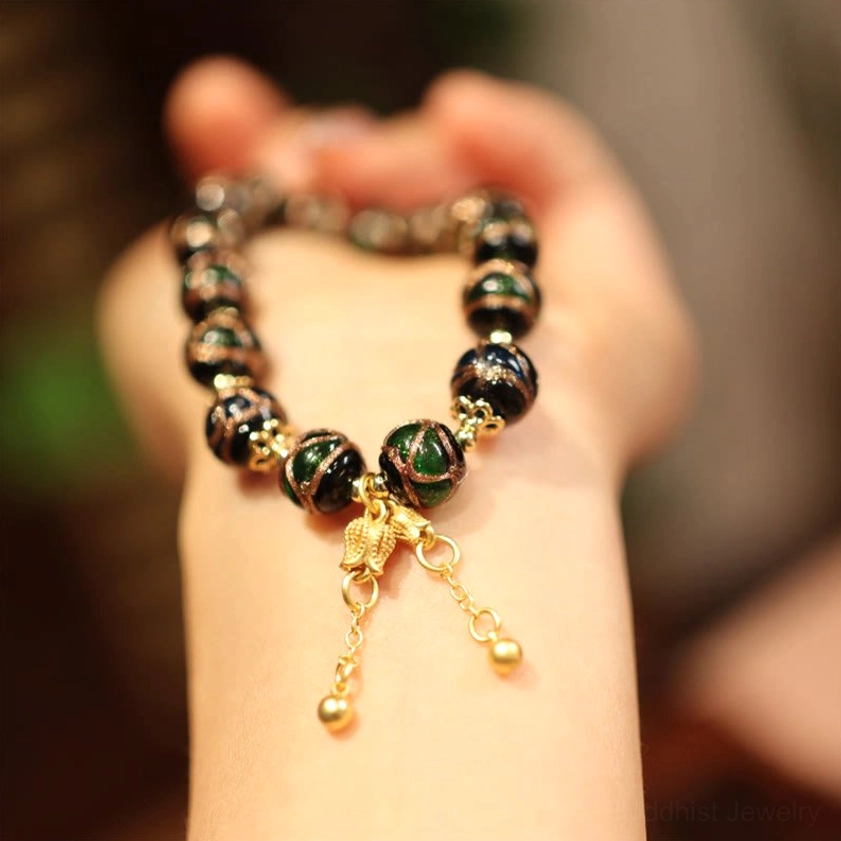 Buddhist prosperity bracelet with gold chain tassel charm pendants and dark stone beads on wrist