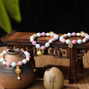 Handcrafted Buddhist prosperity bracelet with liuli glass beads, rabbit enamel charm, and gold accents displayed on zen-themed wooden table with incense holder