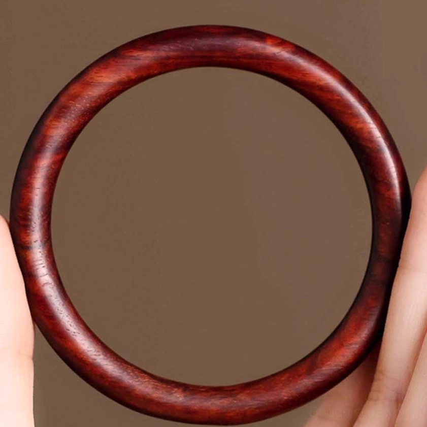 Reddish-brown Wood Buddhist Bangle held by fingers - side close-up showing polished round design