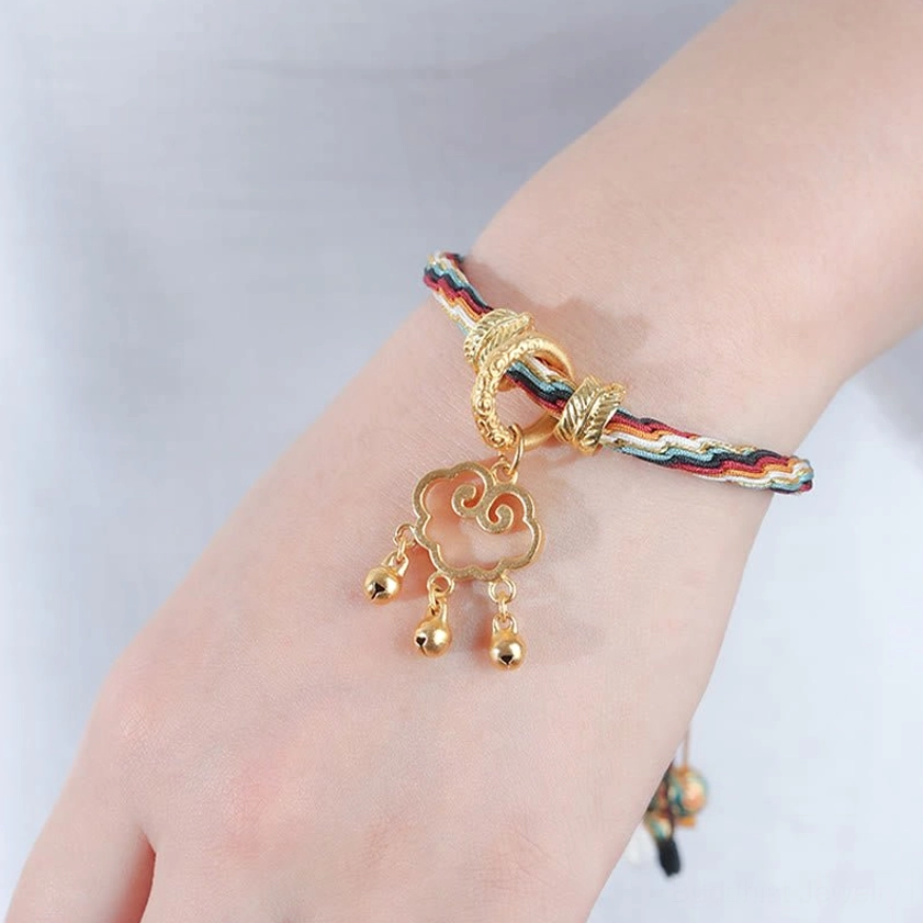 Slim multicolor braided Buddhist protection bracelet with gold decorative buckle, cloud lock pendant and bells on light plain background