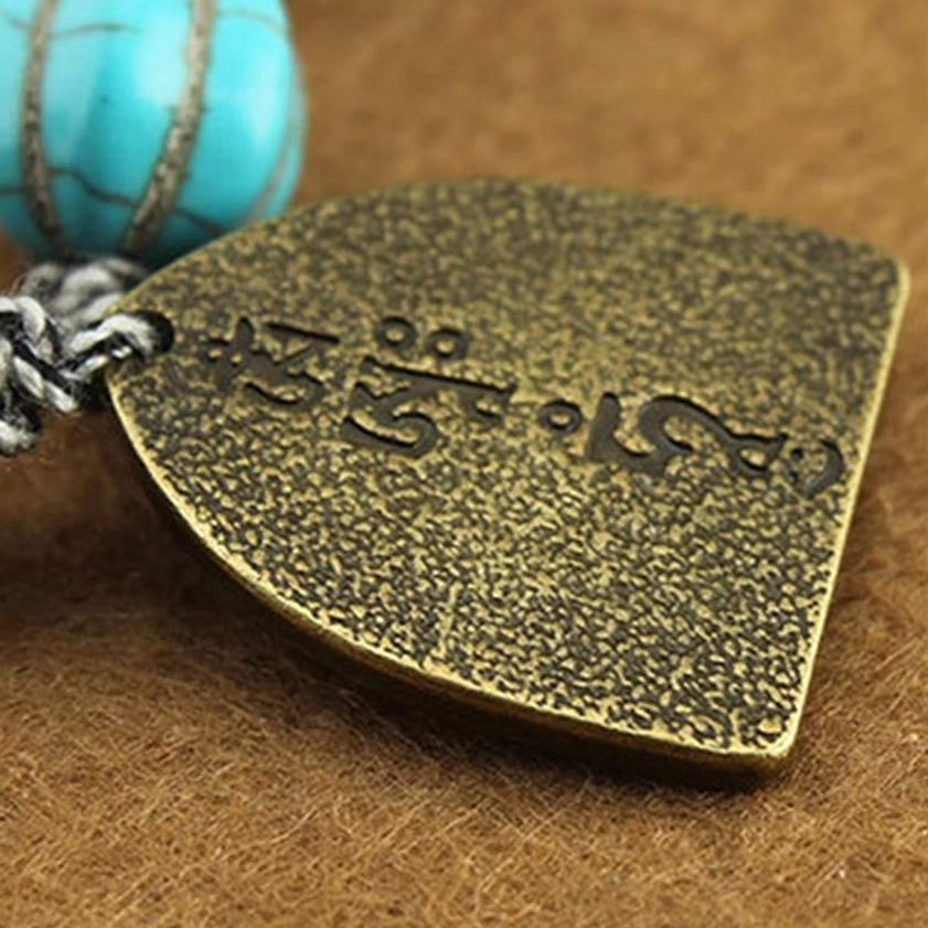Front view of Buddhist protection bracelet displaying turquoise lotus bead and deity guardian charm as focal point