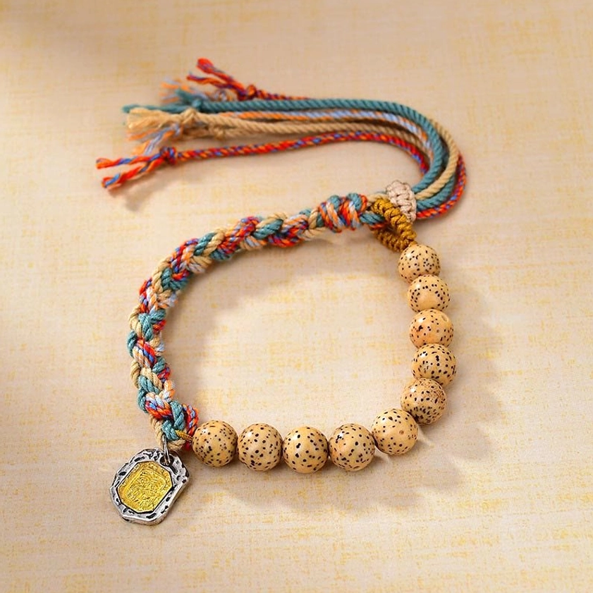 Spiritual protection bracelet with bodhi seeds, multicolor string, and enamel goddess pendant in oblique angle view