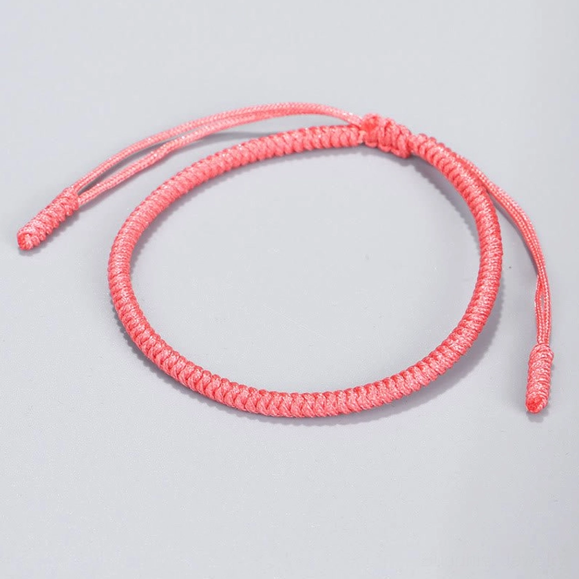 Light pink Buddhist string bracelet with smooth woven rope design and adjustable tassel ends for spiritual protection