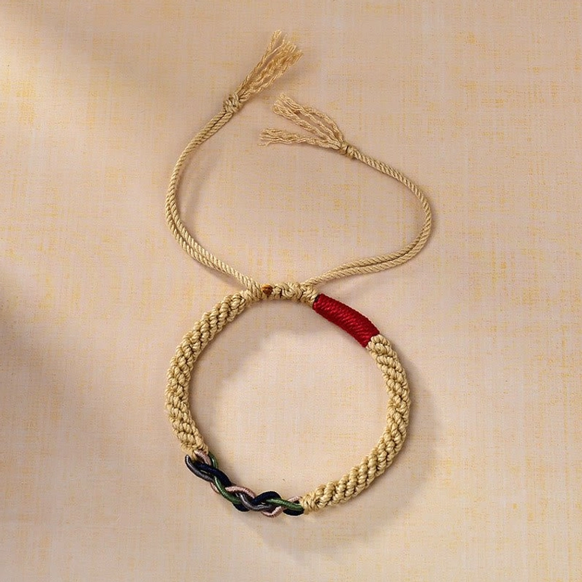 Overhead flat lay of sacred red string Buddhist bracelet with natural fibers, red accent section, and adjustable tassel cord ends
