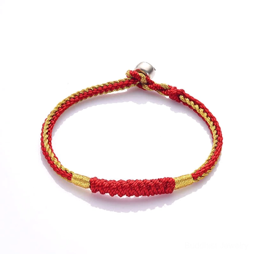 Handmade red and gold braided Buddhist string bracelet featuring thick woven red segment with secure metal clasp, top-down angle