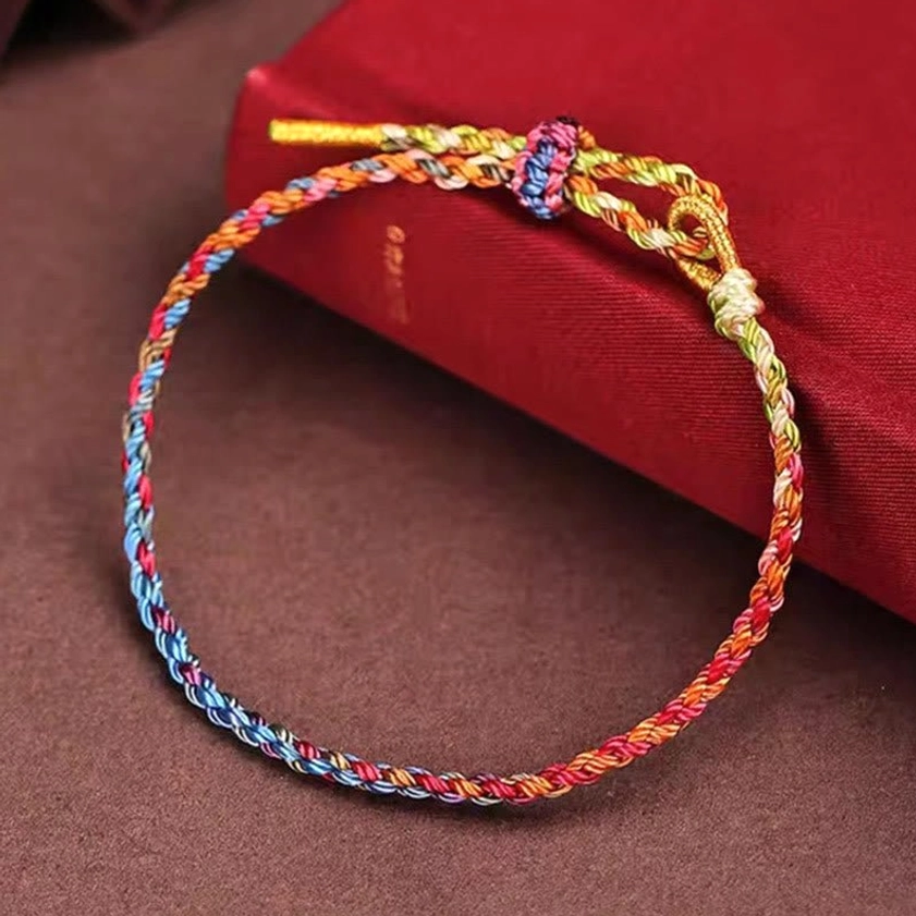 Multicolor woven Buddhist string bracelet with adjustable knot and metal cord ends, oblique side view