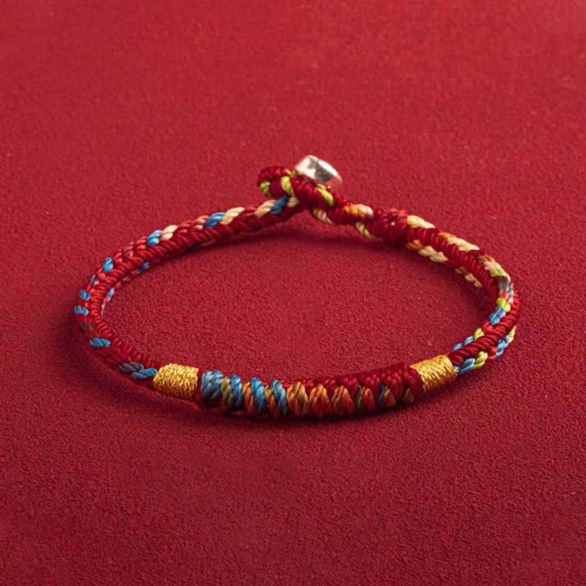 Side angle view of red and multicolored woven Buddhist bracelet with protective silver clasp detail