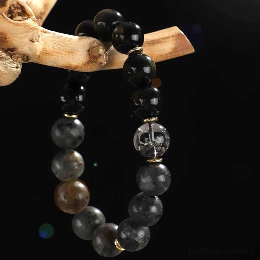natural gemstone buddhist bracelet with black onyx rutilated quartz and sterling silver pendant hanging on wooden branch