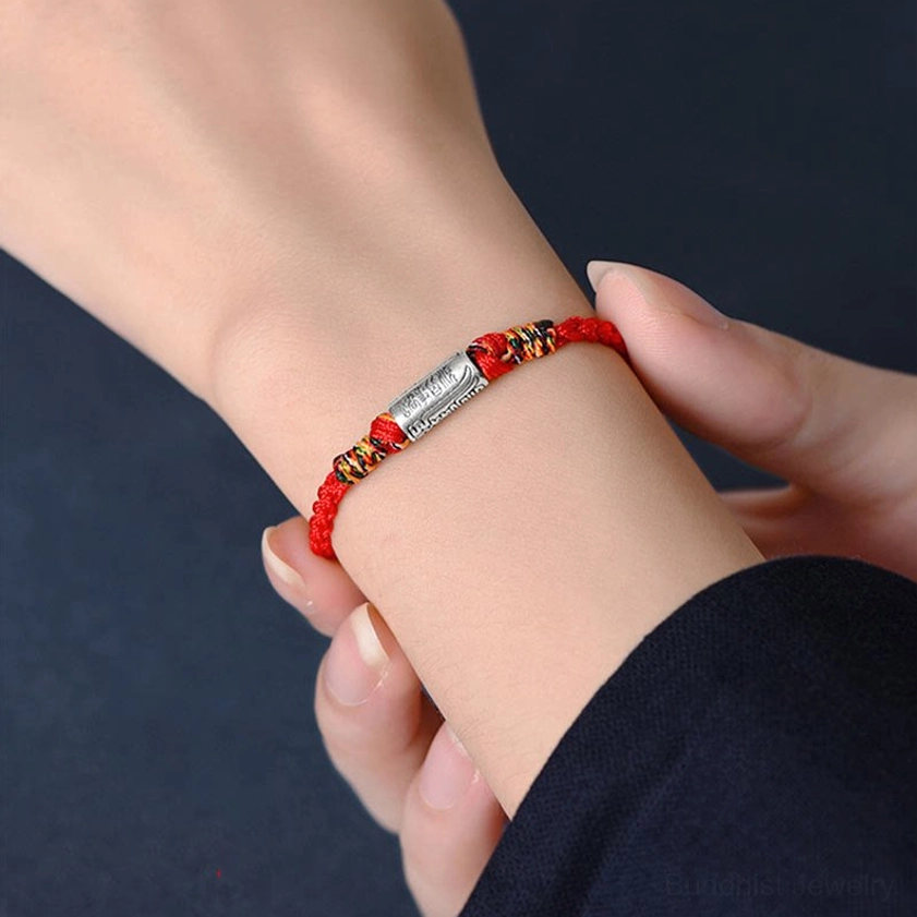 Buddhist blessing bracelet worn on left wrist during daily life, showing how sacred red string charm fits snugly, real-world wearing demonstration