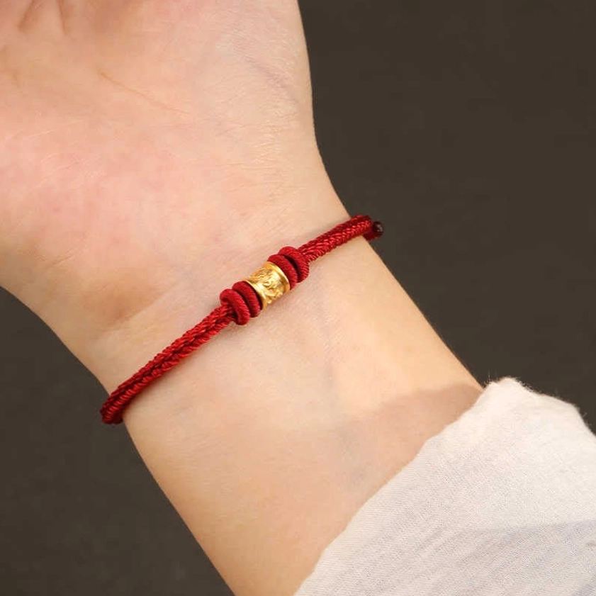 Buddhist red string bracelet being worn on human wrist, real-life wearing demonstration