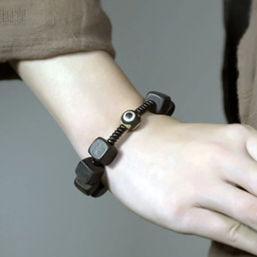 Buddhist protective bracelet featuring ebony wood and sacred dzi bead amulet for daily mindfulness practice