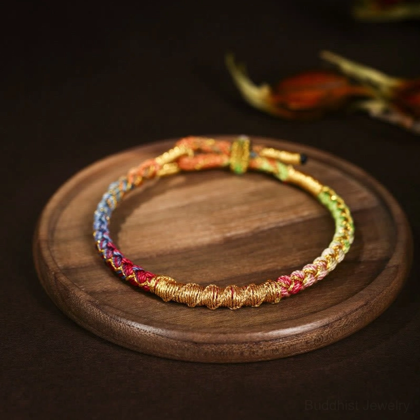 Multi-color rainbow Buddhist braided bracelet with blue green and gold thread accents three-quarter view