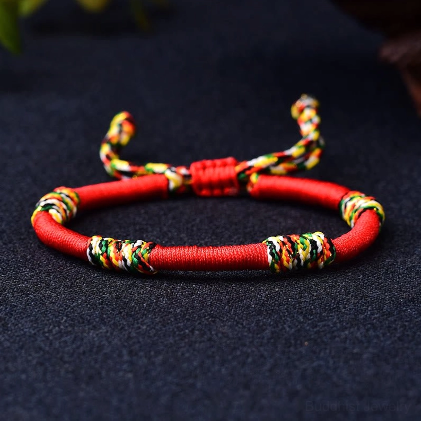 Red Buddhist bracelet overhead view showing colorful sacred knot accents and premium quality weaving