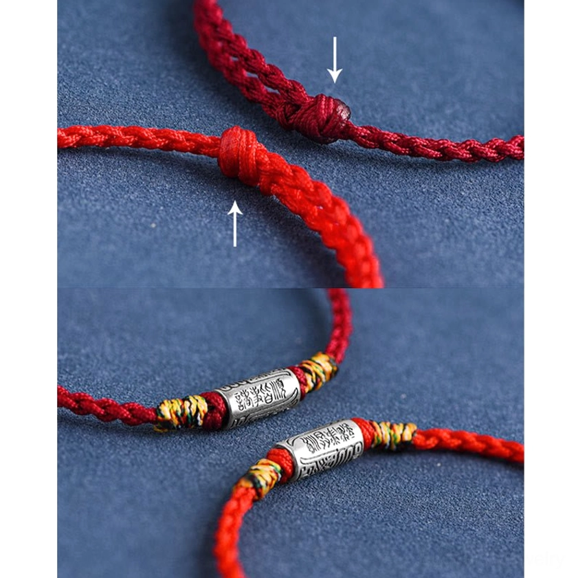Buddhist red rope bracelet with 925 sterling silver charm, displayed on dark blue fabric background highlighting color contrast