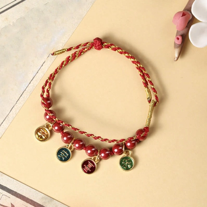 Red string cinnabar bracelet on decorative floral background, showcasing traditional Buddhist spiritual design