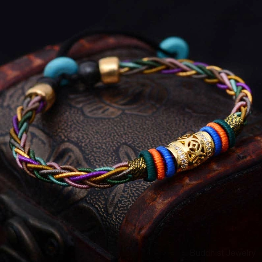 Buddhist red string protection bracelet featuring engraved copper coin charm and turquoise spacer beads on vintage leather surface