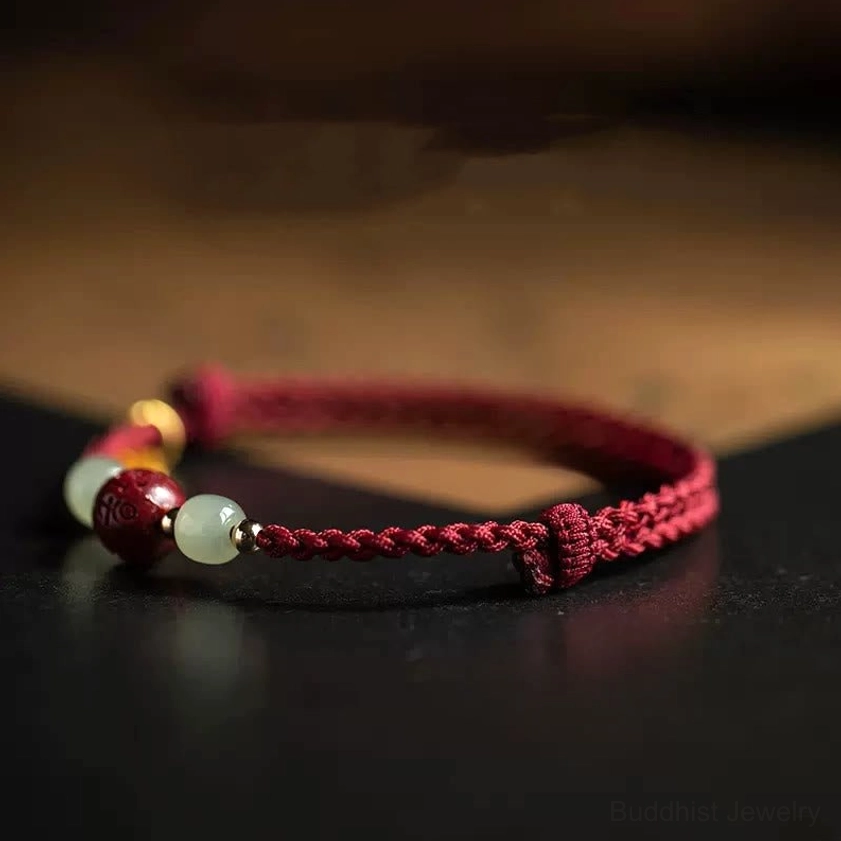 Handmade Buddhist red string bracelet close-up showing woven cord jade beads and gold accents