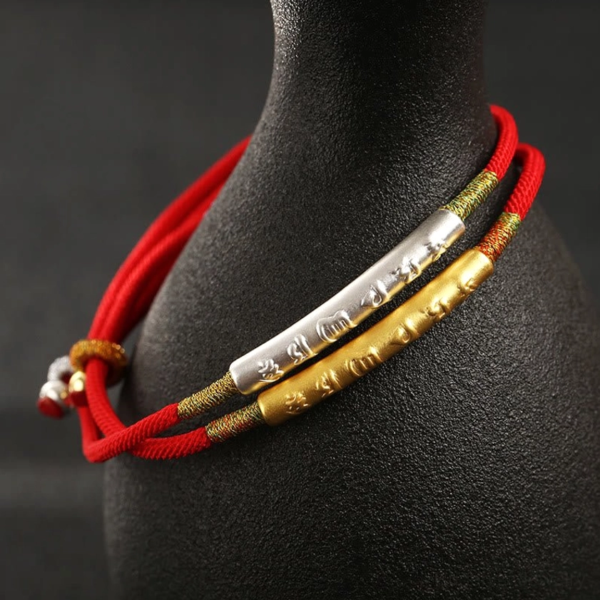 Double-layer Buddhist red string bracelet with sterling silver and gold engraved tubes on black ceramic display stand