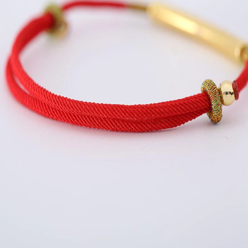 Double-strand Buddhist red string bracelet with gold tube charm and metal adjuster on white background