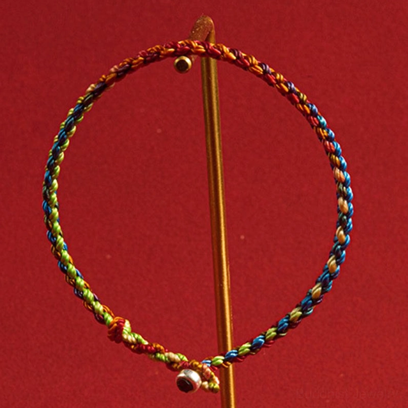 Buddhist protection bracelet with twisted gradient multicolored cord and silver bell clasp on display stand