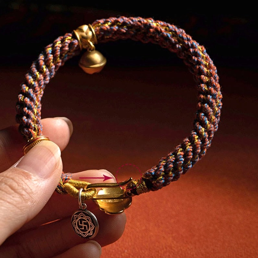 Close-up overhead view of handcrafted red string Buddhist bracelet with removable sterling silver charm