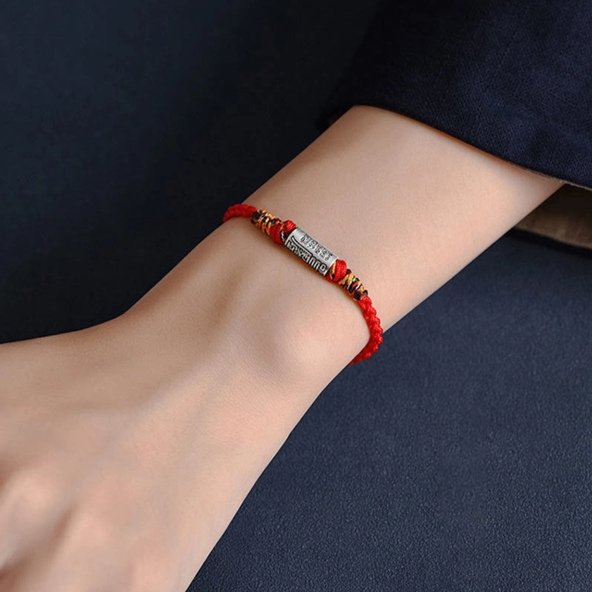 Side view of worn Buddhist red string bracelet on right wrist, demonstrating comfortable fit and spiritual charm during everyday activities