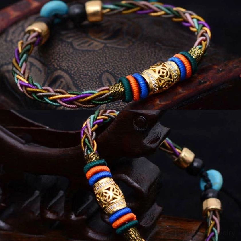 Detailed overhead close-up of handmade Buddhist red string bracelet showing woven texture and metal coin charm on vintage leather surface