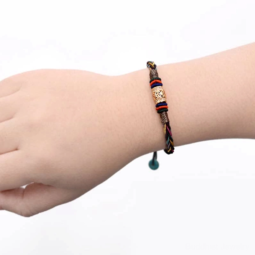 Worn on wrist showing slim woven Buddhist red string bracelet design with stacked metal decorative beads and dangling adjustable end