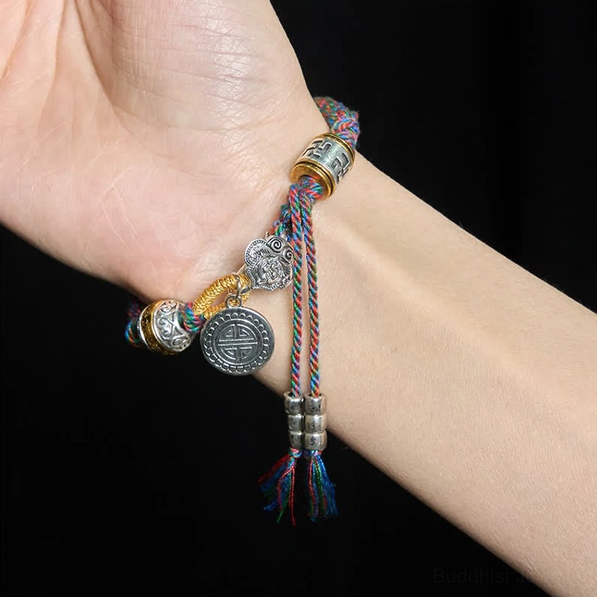 Buddhist Symbols Braided Bracelet Worn on Wrist with Silver Charm Details Against Black Background