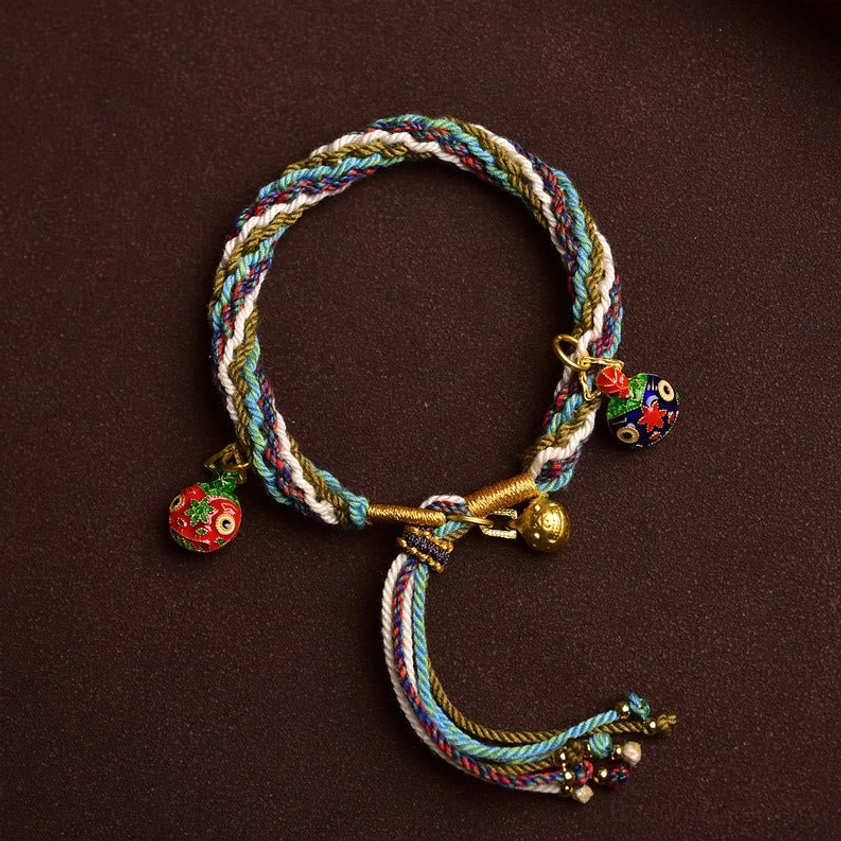 Multicolor handmade Buddhist protection bracelet with three Swallowing Beast enamel pendants and tassel flat lay