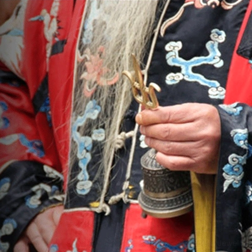 Buddhist monk in traditional embroidered robe performing ritual with meditation bell, authentic spiritual practice demonstration