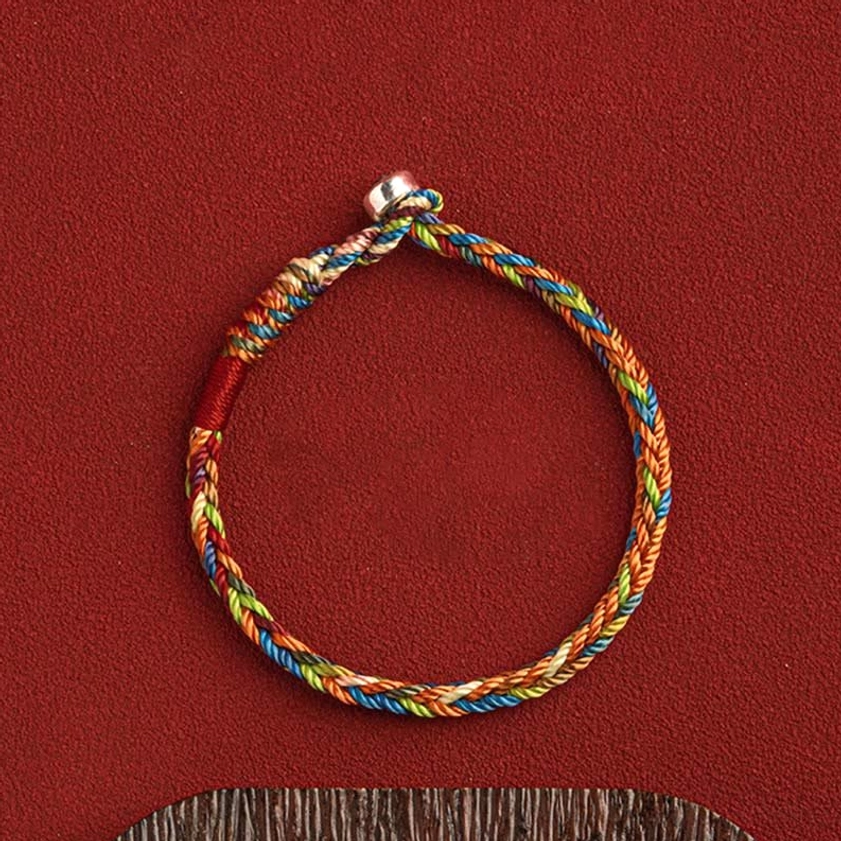 Flat lay of multicolor Buddhist bracelet with silver clasp and gift accessories on neutral background