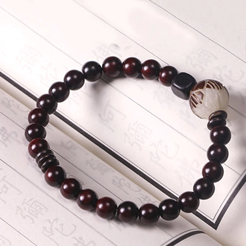 Single wrap beaded bracelet on ancient book page background, displaying reddish-brown sandalwood wooden beads and sculptured lotus focal bead