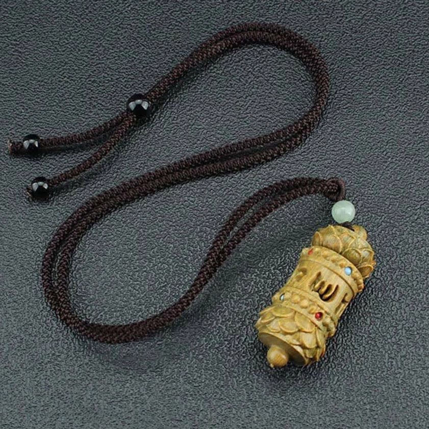 Two matching handcrafted Buddhist pendant necklaces with black adjuster beads and light green aventurine details on dark tabletop