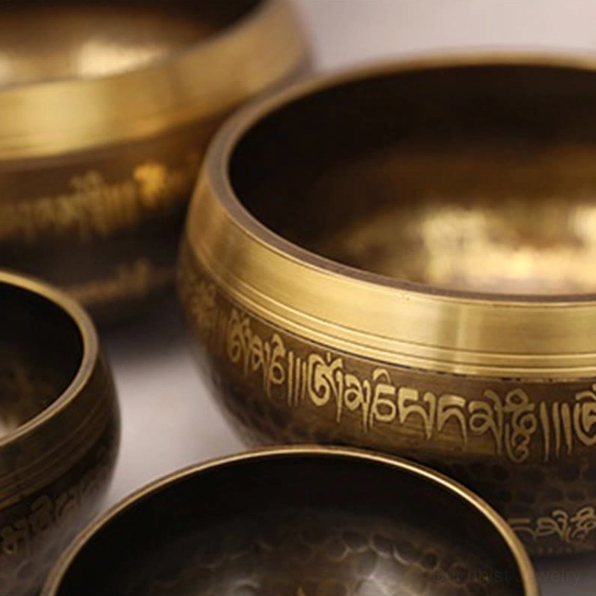 Buddhist singing bowl collection display featuring multiple handcrafted bowls in different sizes with Sanskrit mantras and hammered bronze surfaces