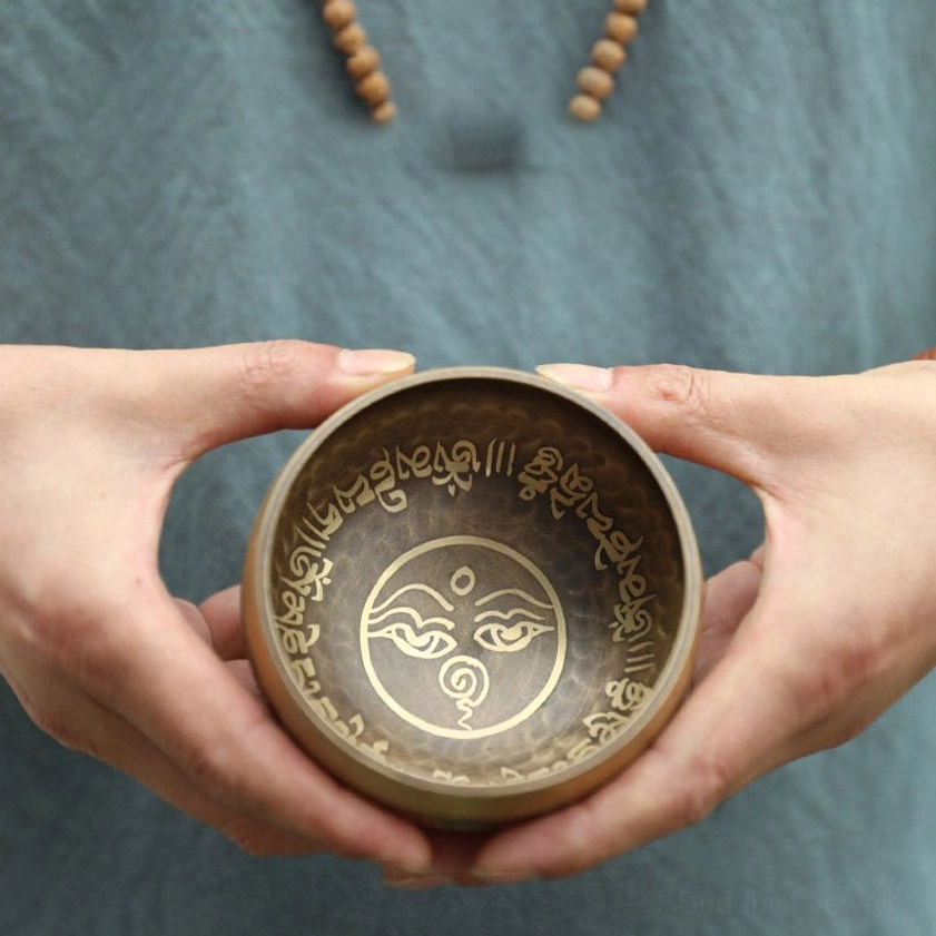 Compact mini Buddhist singing bowl on soft fabric background, showing standard sacred symbols and handcrafted quality