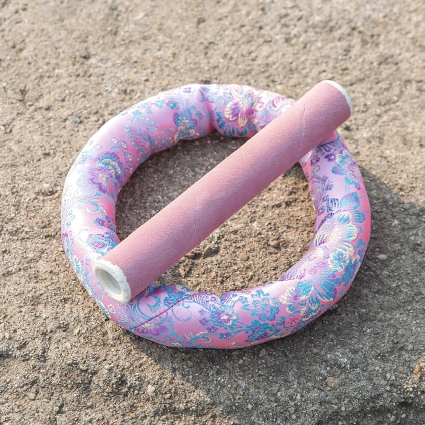 Buddhist singing bowl meditation cushion with pink floral fabric and leather striker mallet in overhead view