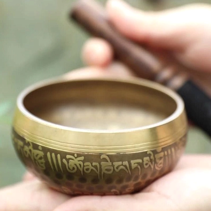 Buddhist singing bowl close-up showing smooth golden inner surface and exterior engraved sacred text