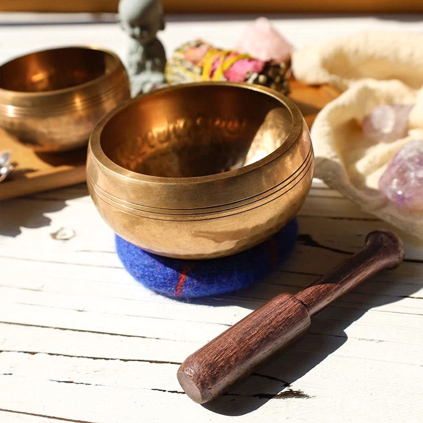 Buddhist singing bowl meditation set displayed with healing crystals and ceremonial accessories on tabletop, perfect for chakra alignment and energy healing practice